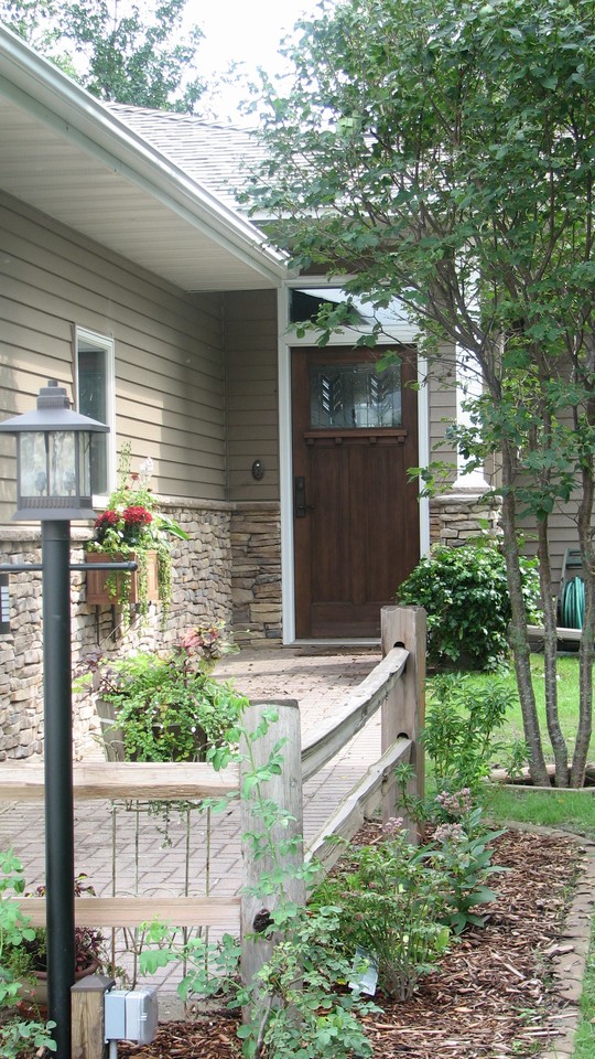 summer picture of front door, siding, and landscaping.