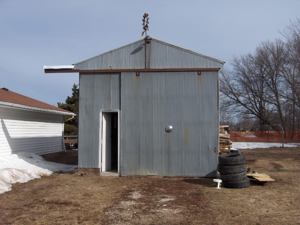 shed in backyard has cement floor, wood burner, and it's own electrical service.