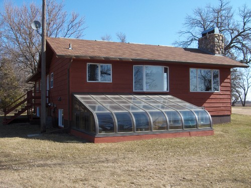 side of house shows newer roof and addition of a sunroom off of the basement.