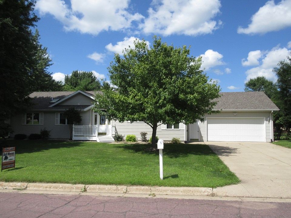 front of home vinyl siding, aluminum shutters and soffit, attached double garage, mature trees and landscaping